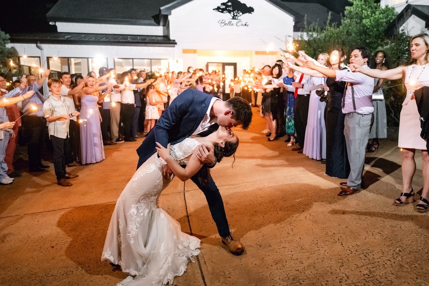 Guests holding sparklers at a wedding exit beside the Bella Oaks sign