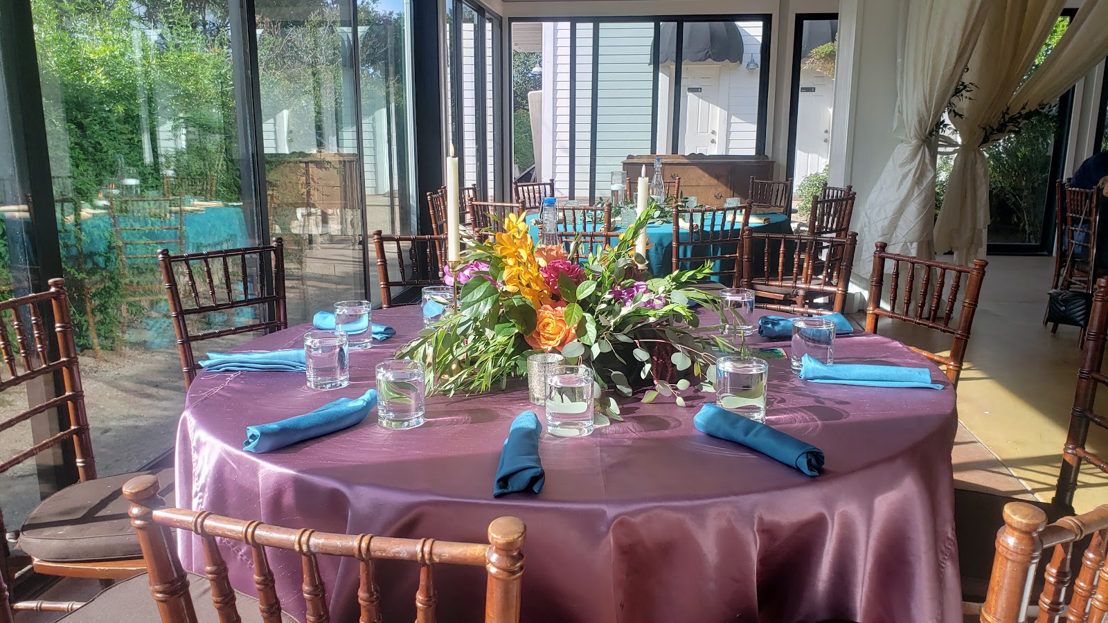 A reception table with a flower centerpiece beside the hall windows