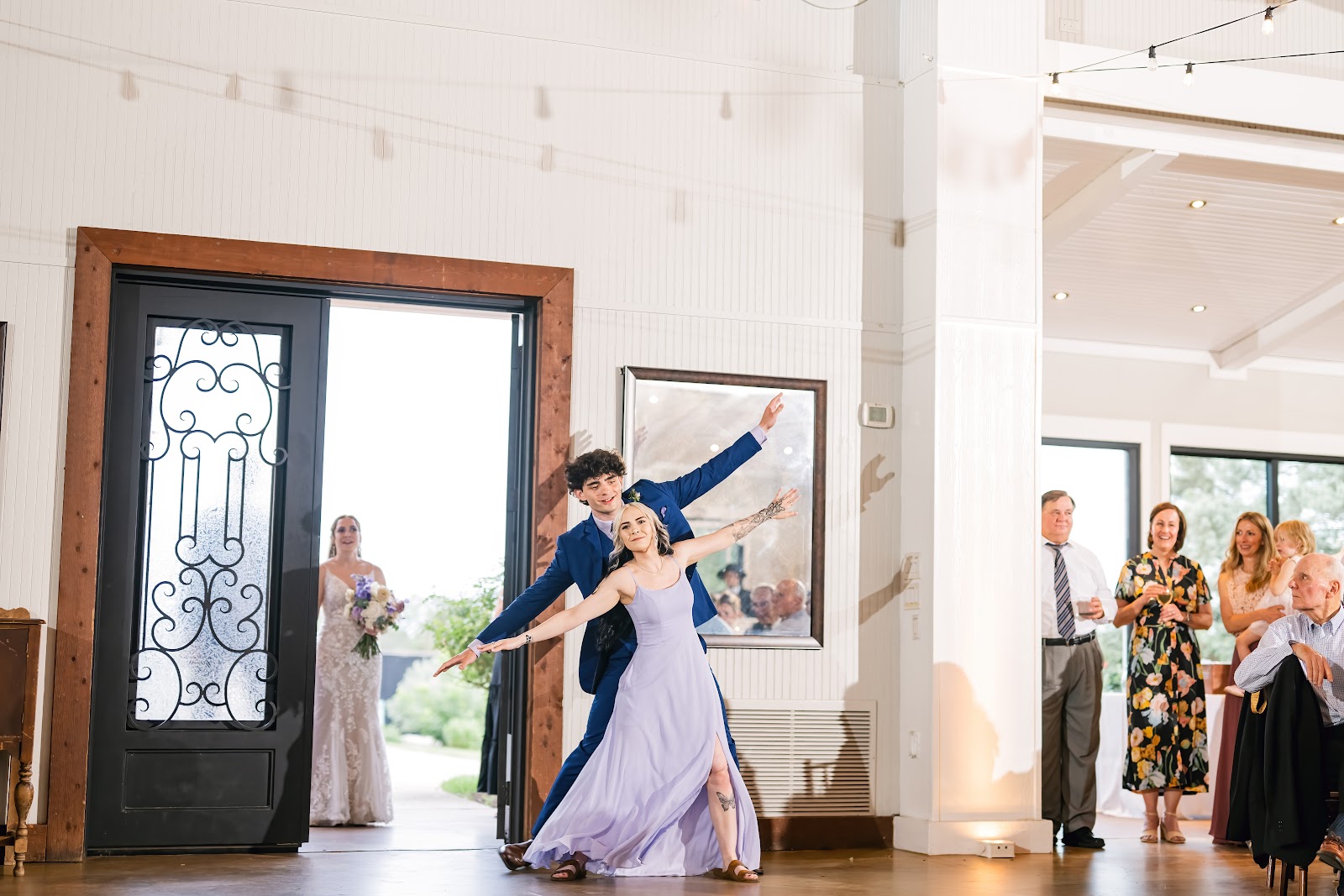 Guests watching a dance in the indoor hall with white paneled walls