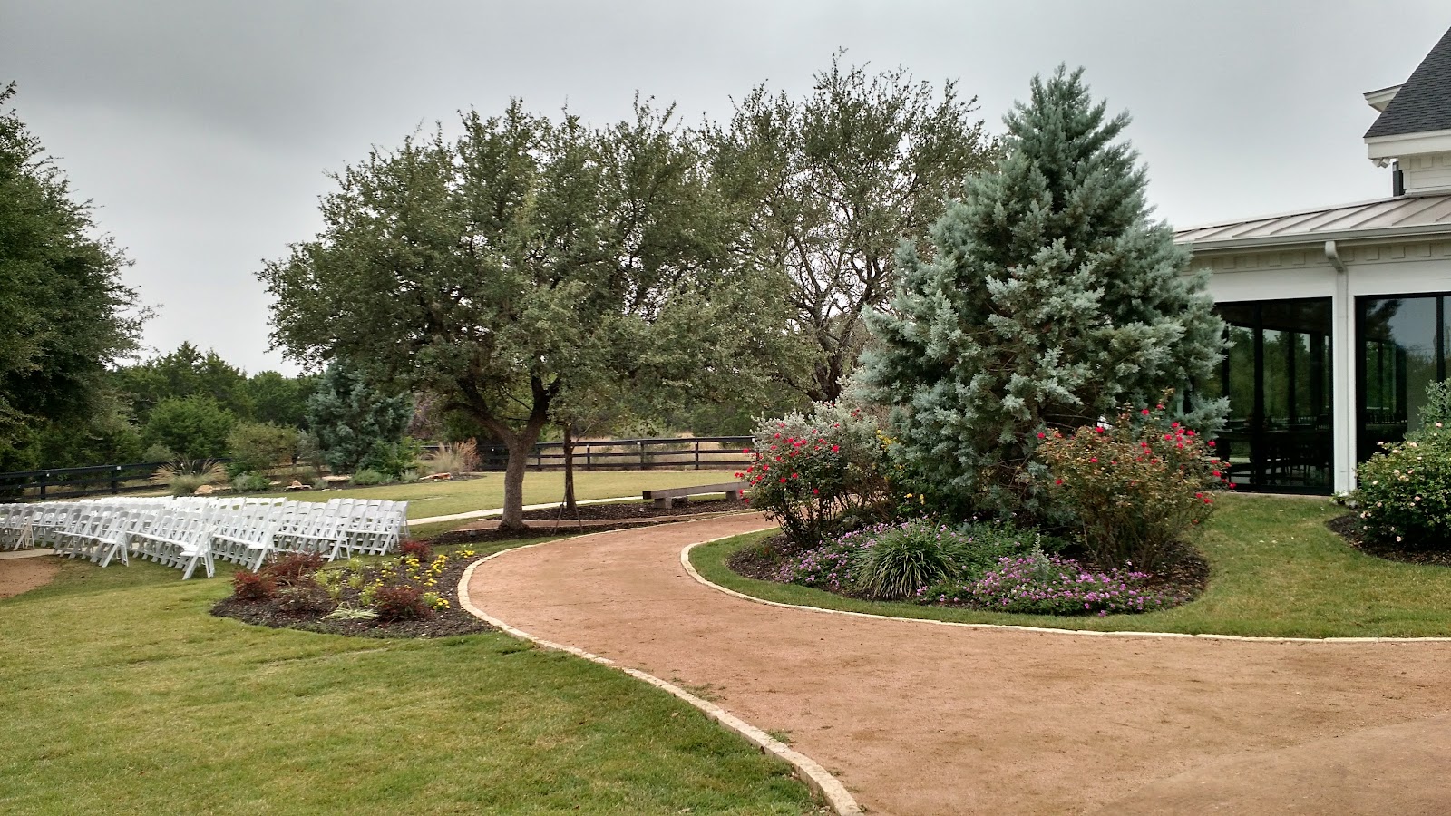A gravel path winding past gardens and rows of white chairs for a ceremony